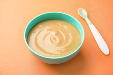 Photo of Bowl of healthy baby food on color background