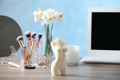 Photo of Beautiful female body shaped candle on wooden table indoors