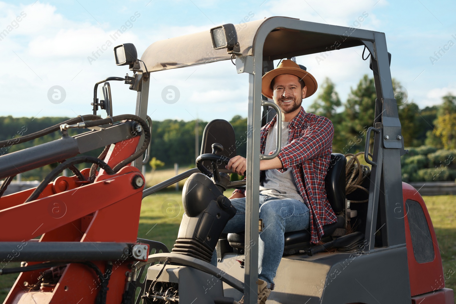 Photo of Smiling farmer driving loader outdoors. Agriculture equipment