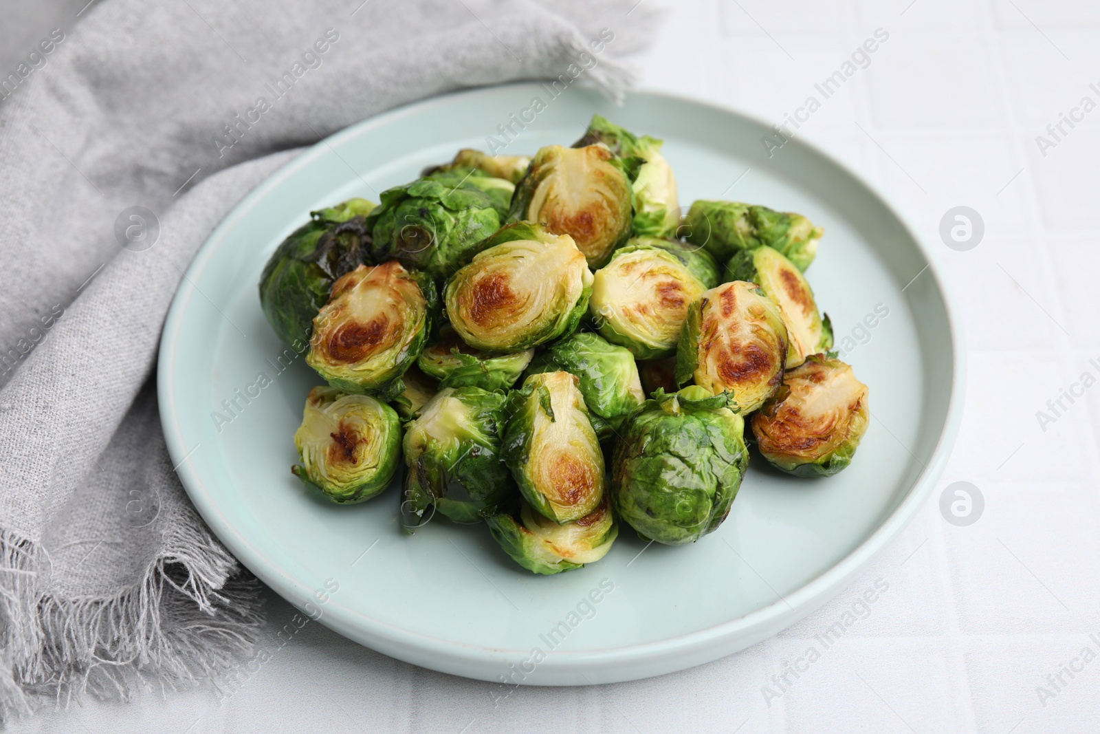 Photo of Delicious roasted Brussels sprouts on white tiled table