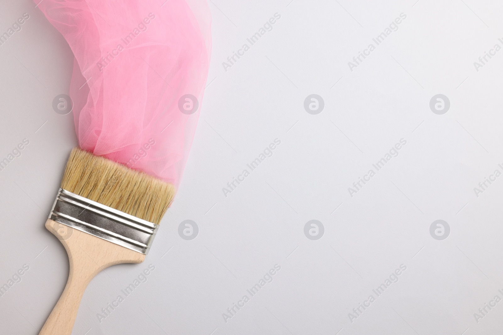 Photo of Brush painting with pink tulle on light background, top view. Space for text. Creative concept