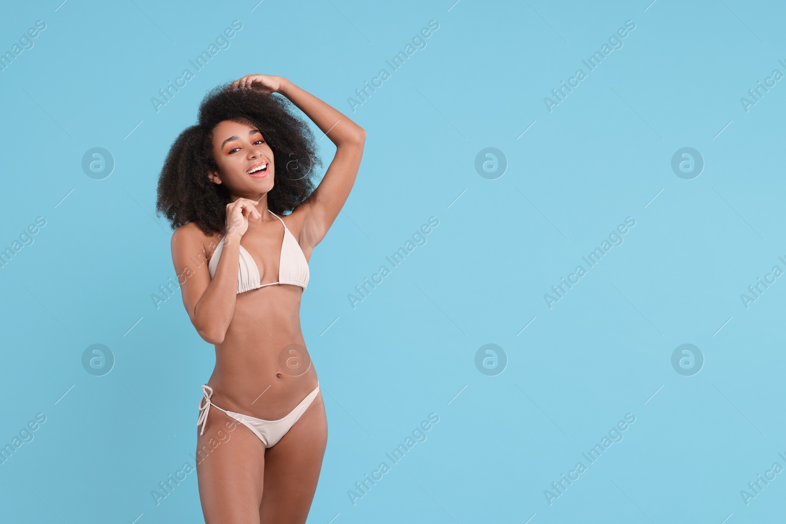 Photo of Beautiful woman in stylish bikini on light blue background, space for text