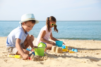 Photo of Cute little children playing with plastic toys on sandy beach