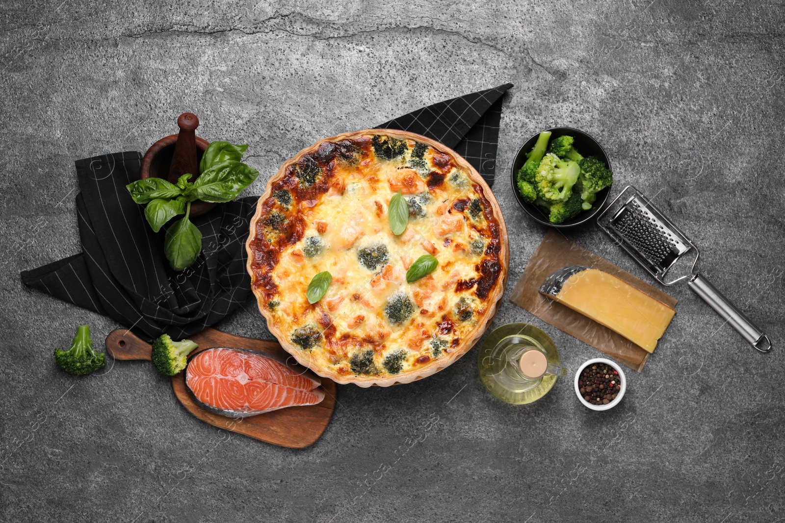 Photo of Delicious homemade quiche and ingredients on gray table, flat lay