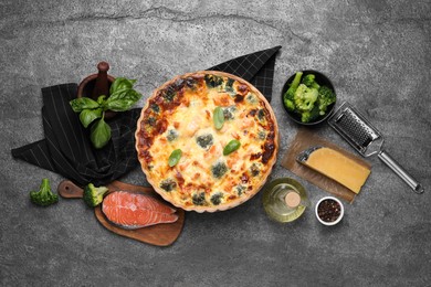 Photo of Delicious homemade quiche and ingredients on gray table, flat lay