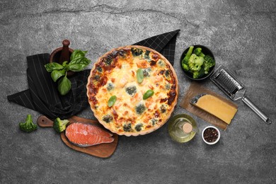 Delicious homemade quiche and ingredients on gray table, flat lay