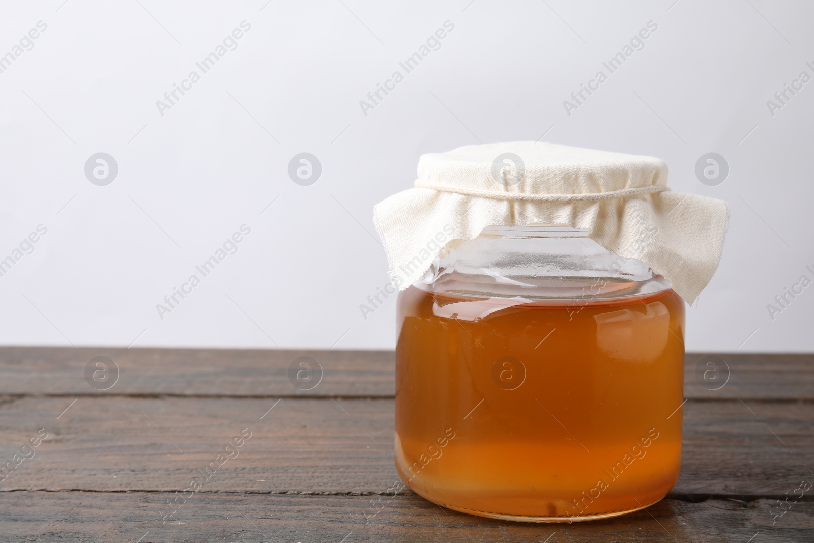 Photo of Homemade fermented kombucha in glass jar on wooden table. Space for text