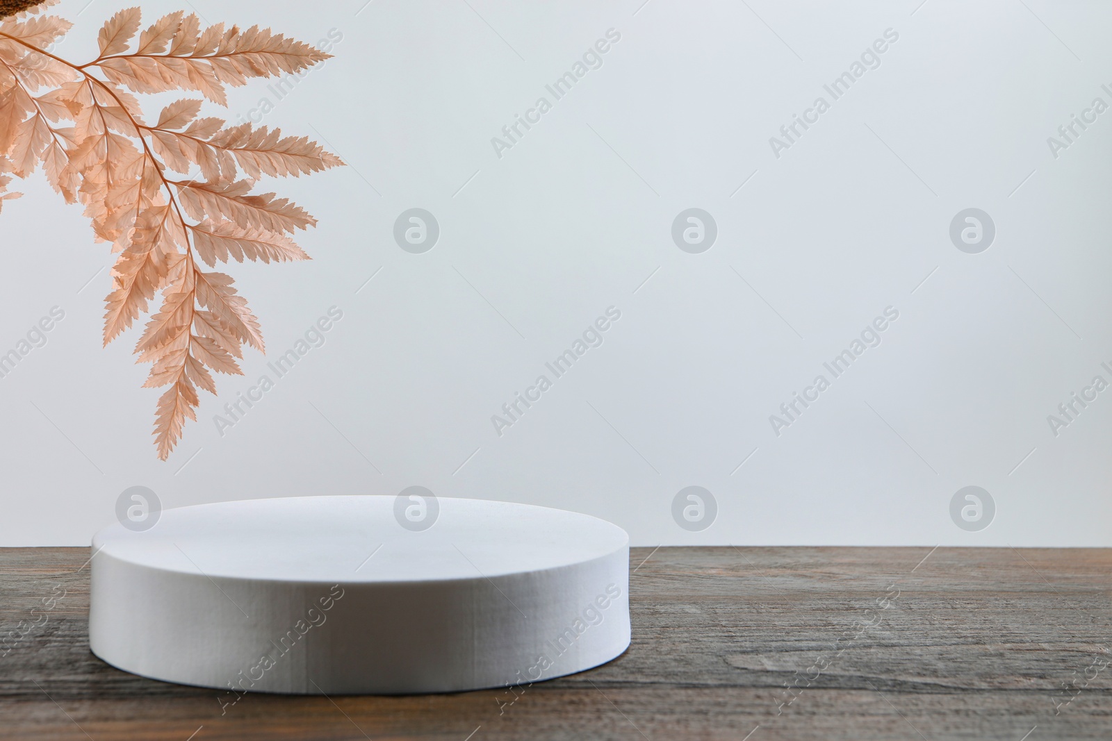 Photo of Pink leaves and round shaped podium on wooden table. Space for text