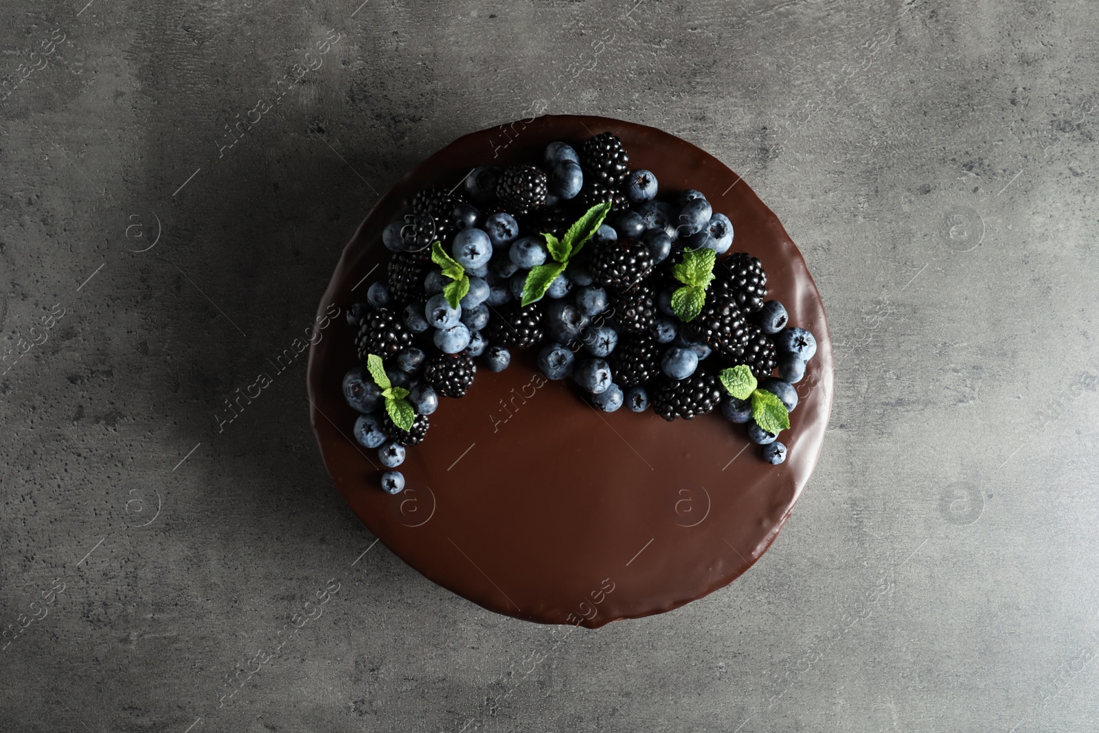 Photo of Fresh delicious homemade chocolate cake with berries on gray table, top view