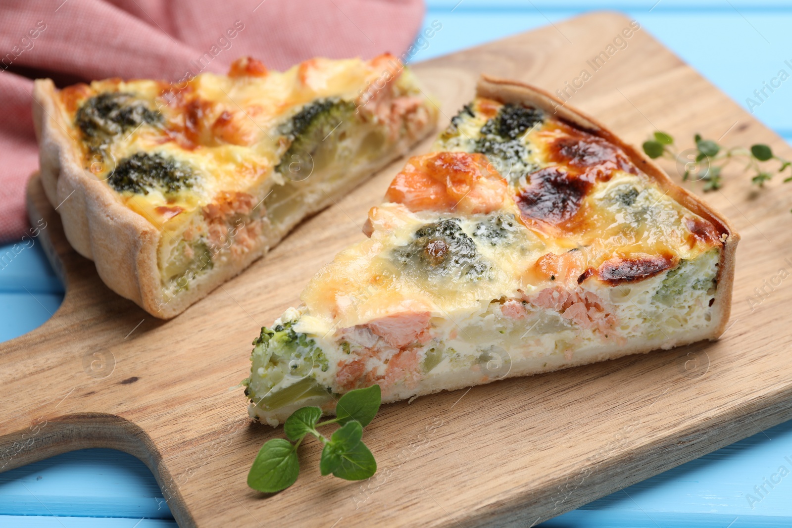 Photo of Delicious homemade quiche with salmon and broccoli on wooden board, closeup