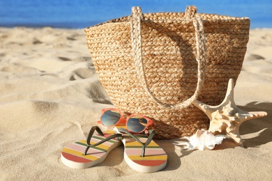 Photo of Set with stylish beach accessories on sand near sea