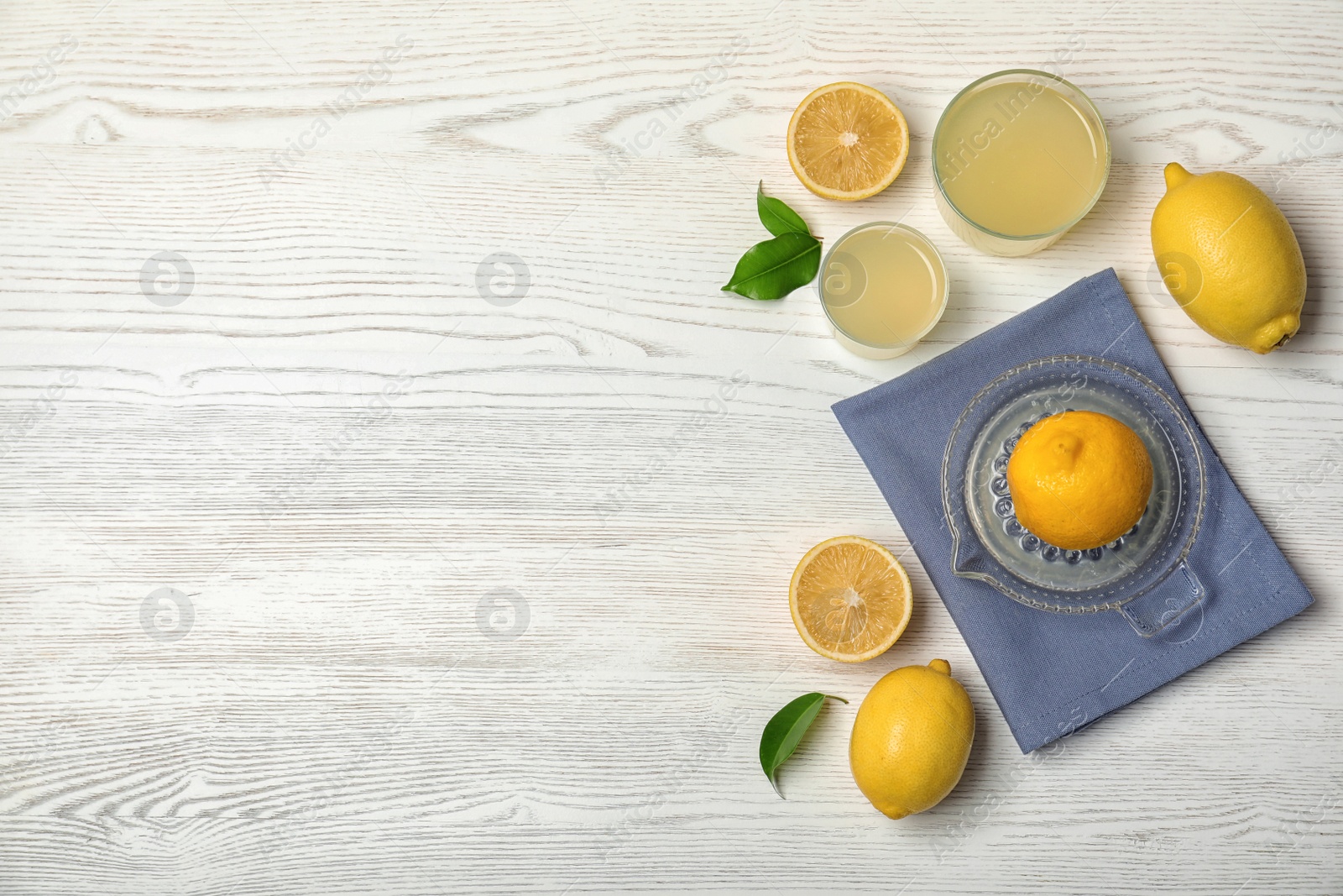 Photo of Flat lay composition with freshly squeezed lemon juice and space for text on wooden background