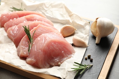 Photo of Cut raw turkey fillet and ingredients on board, closeup