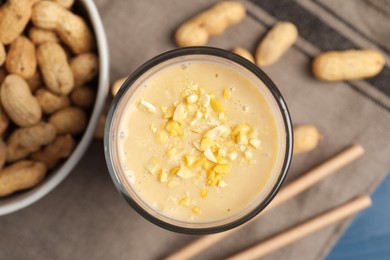 Photo of Glass of tasty banana smoothie with peanuts on table, flat lay