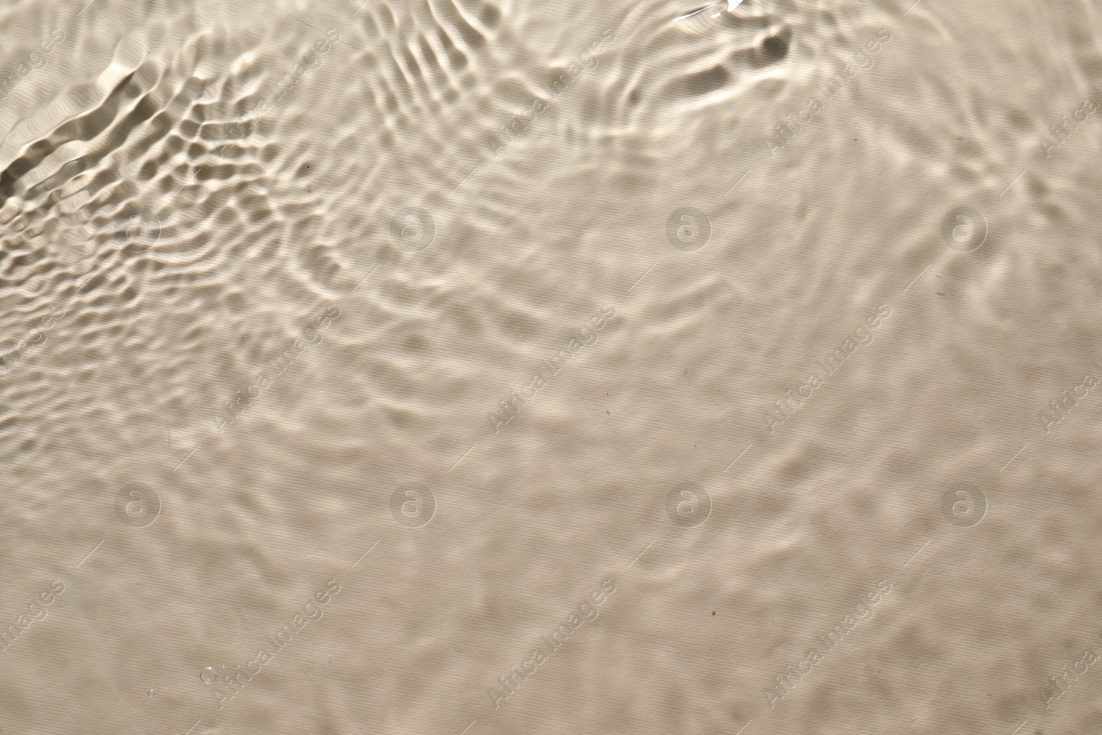 Photo of Rippled surface of clear water on beige background, top view