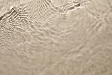 Rippled surface of clear water on beige background, top view