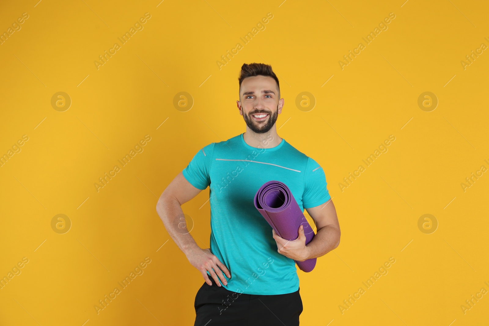 Photo of Handsome man with yoga mat on yellow background