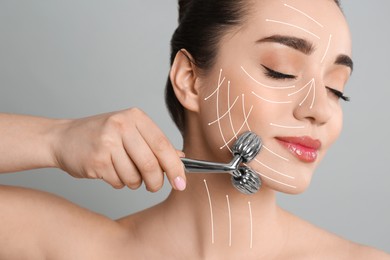 Image of Woman using metal face roller on grey background, closeup