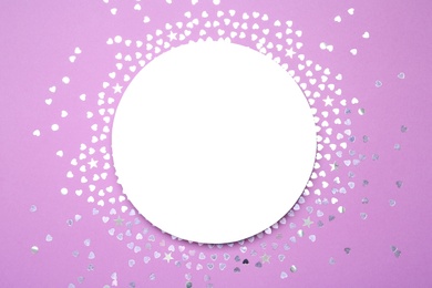 Photo of Frame made of bright confetti and card on violet background, flat lay. Space for text