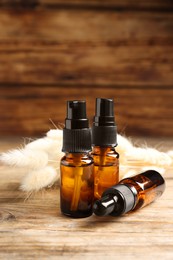 Bottles with oil and fluffy wildflowers on wooden table, space for text. Natural cosmetics