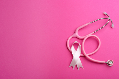 Photo of Pink ribbon and stethoscope on color background, flat lay with space for text. Breast cancer concept