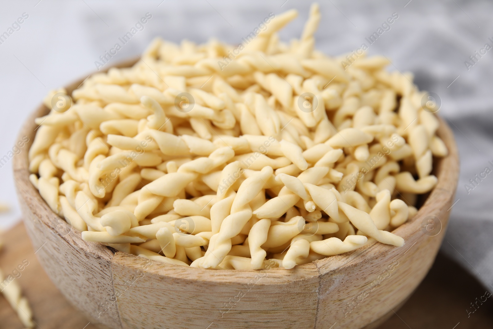 Photo of Uncooked trofie pasta in bowl on table, closeup