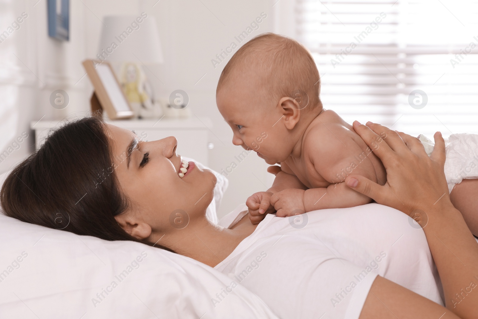 Photo of Happy young mother with her cute baby on bed at home