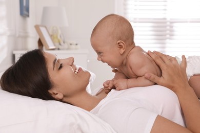 Happy young mother with her cute baby on bed at home