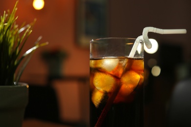 Photo of Glass of cold cola in dark room, closeup. Space for text