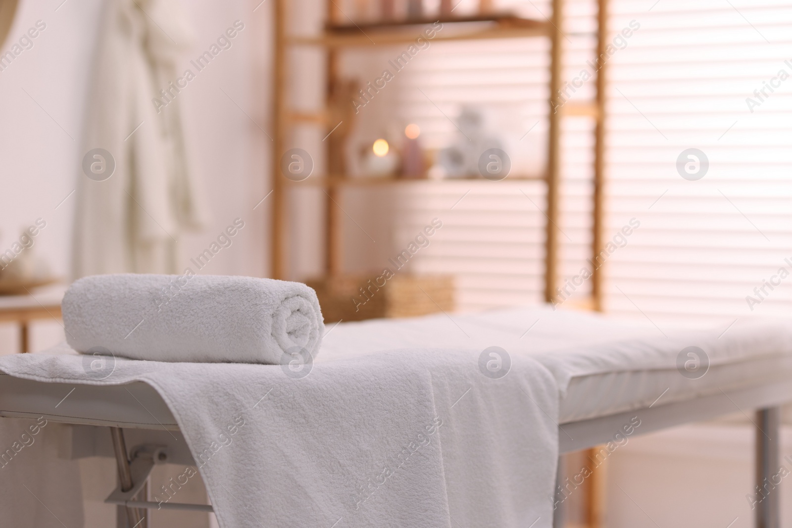 Photo of Rolled towel on massage table in spa center. Space for text