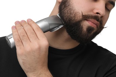 Handsome young man trimming beard on white background, closeup