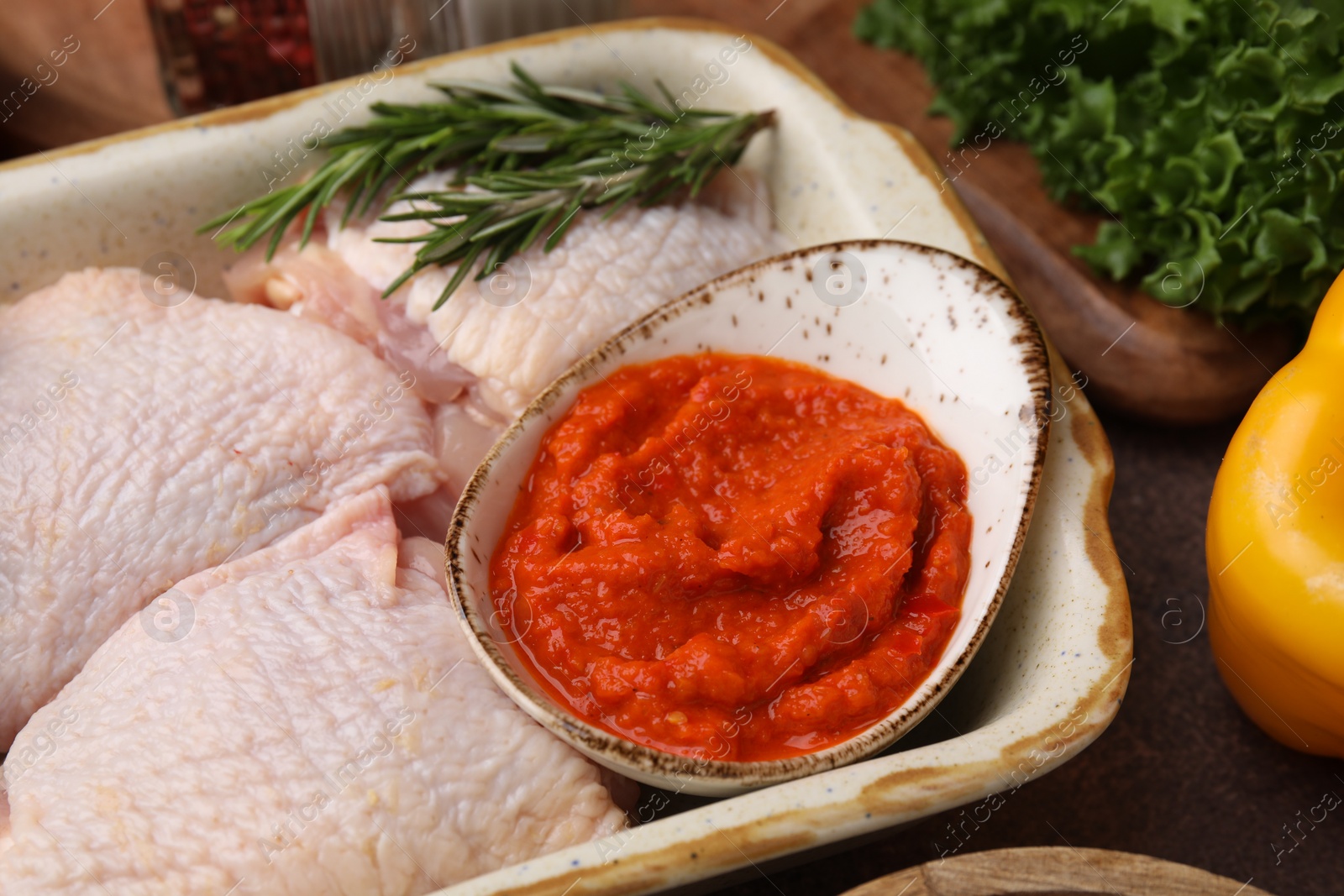 Photo of Fresh marinade, raw chicken and rosemary on table, closeup