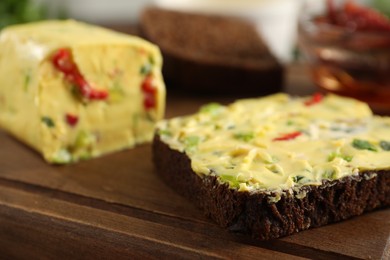 Photo of Tasty butter with green onion, chili pepper and rye bread on wooden board, closeup