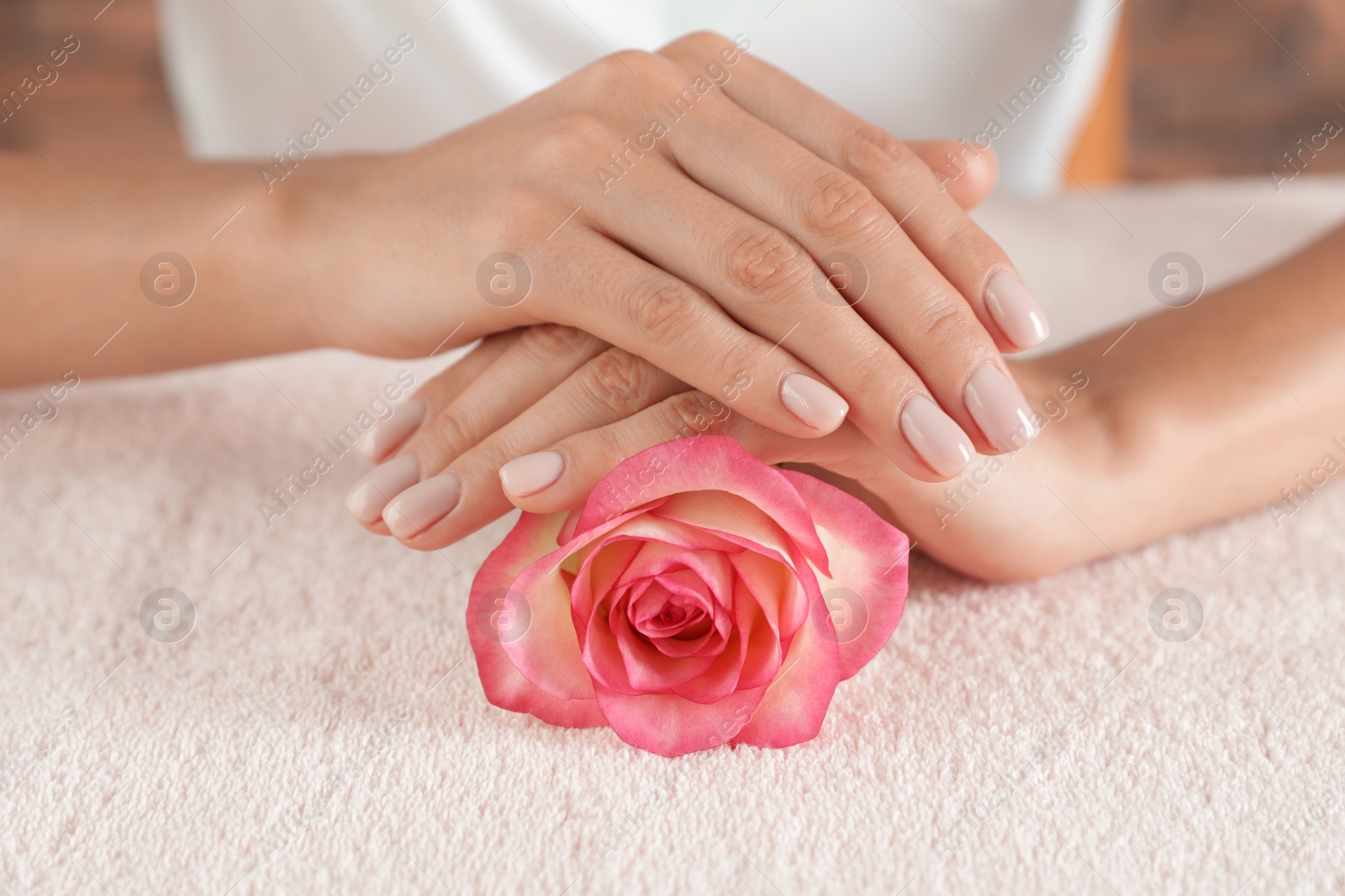 Photo of Woman with smooth hands and flower on towel, closeup. Spa treatment