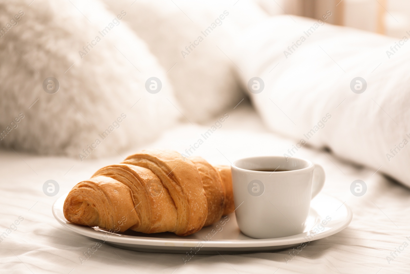 Photo of Delicious morning coffee and croissant on bed