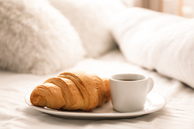 Photo of Delicious morning coffee and croissant on bed