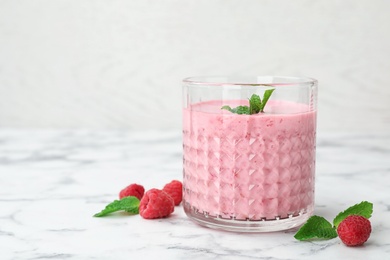 Photo of Delicious smoothie with raspberries in glass on marble table