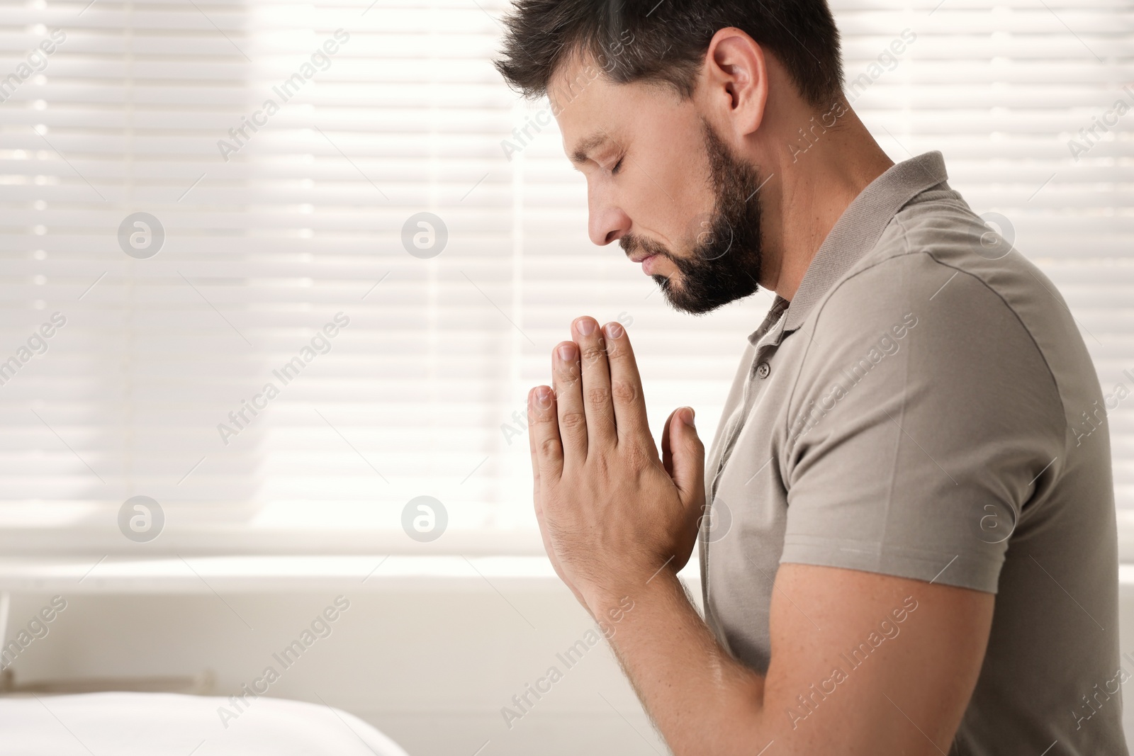 Photo of Religious man praying indoors. Space for text