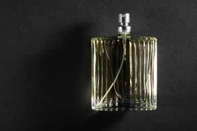 Photo of Luxury men`s perfume in bottle on black background, top view. Space for text