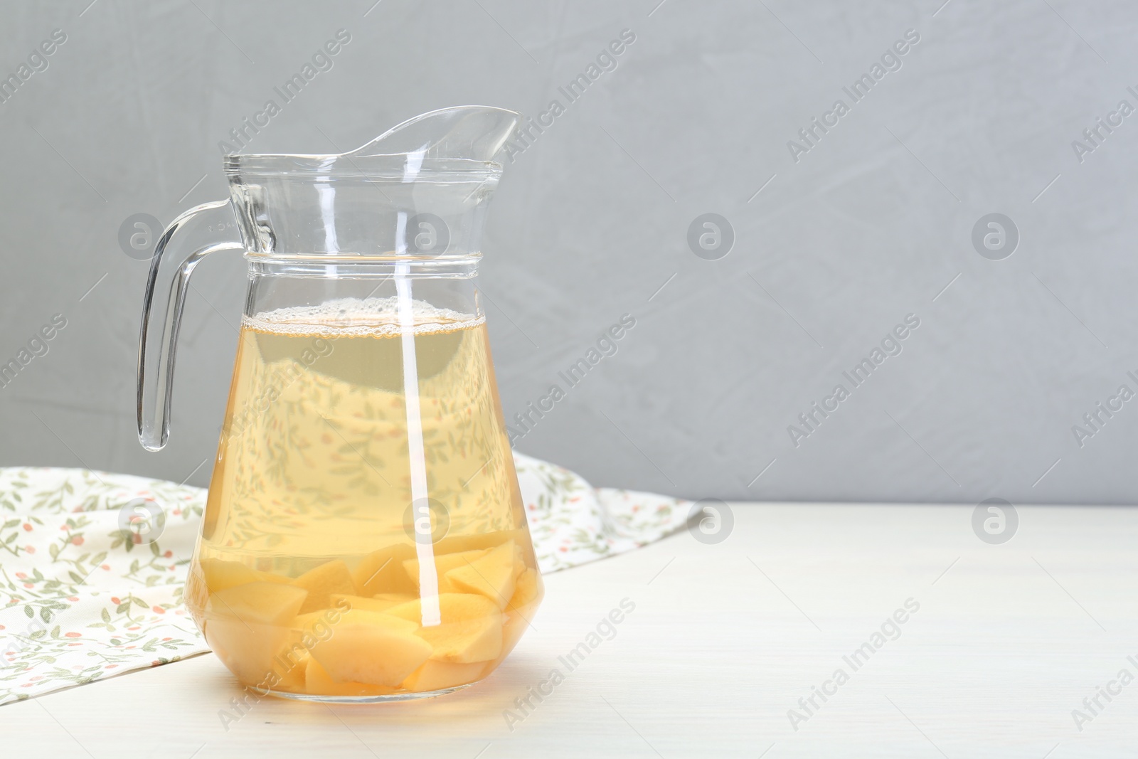 Photo of Delicious quince drink in glass jug on white wooden table, space for text