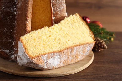 Photo of Delicious Pandoro cake with powdered sugar and Christmas decor on wooden table, closeup. Traditional Italian pastry