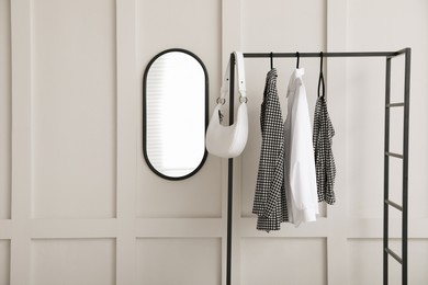 Photo of Simple hallway interior with clothing rack and mirror on light textured wall