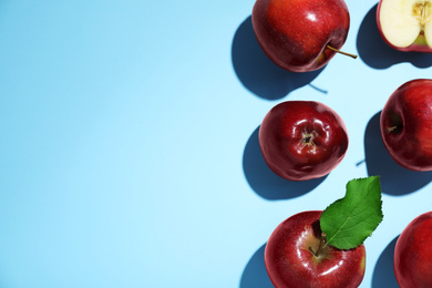 Tasty red apples on light blue background, flat lay. Space for text