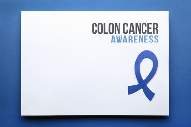 Photo of Card with words COLON CANCER AWARENESS and blue ribbon on color background, top view. Space for text