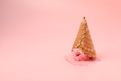 Photo of Melted ice cream in wafer cone on pink background. Space for text