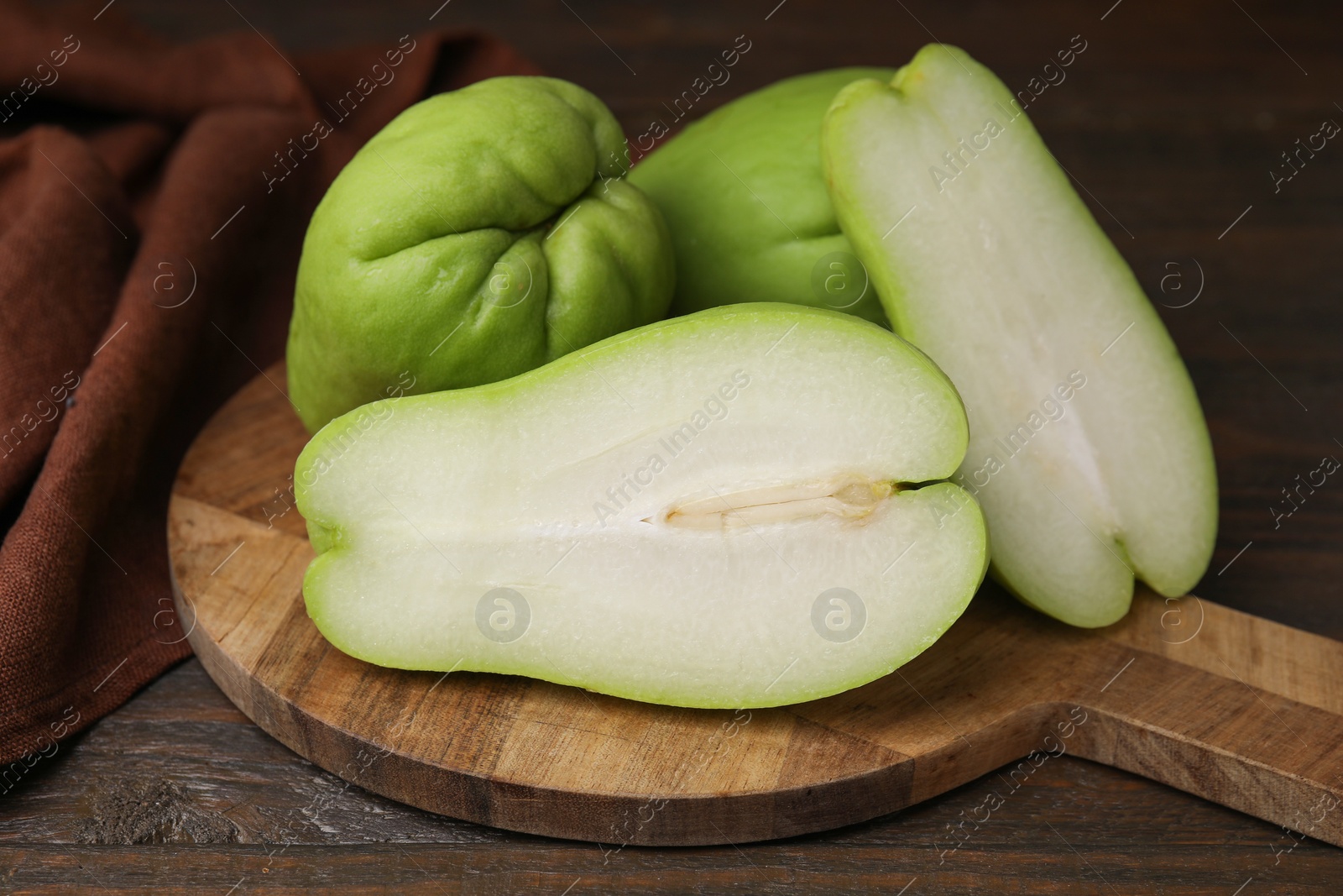 Photo of Cut and whole chayote on wooden table, closeup