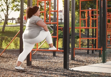 Beautiful overweight woman training on sports ground