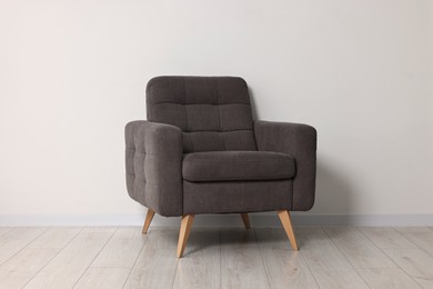 Comfortable armchair near white wall in room