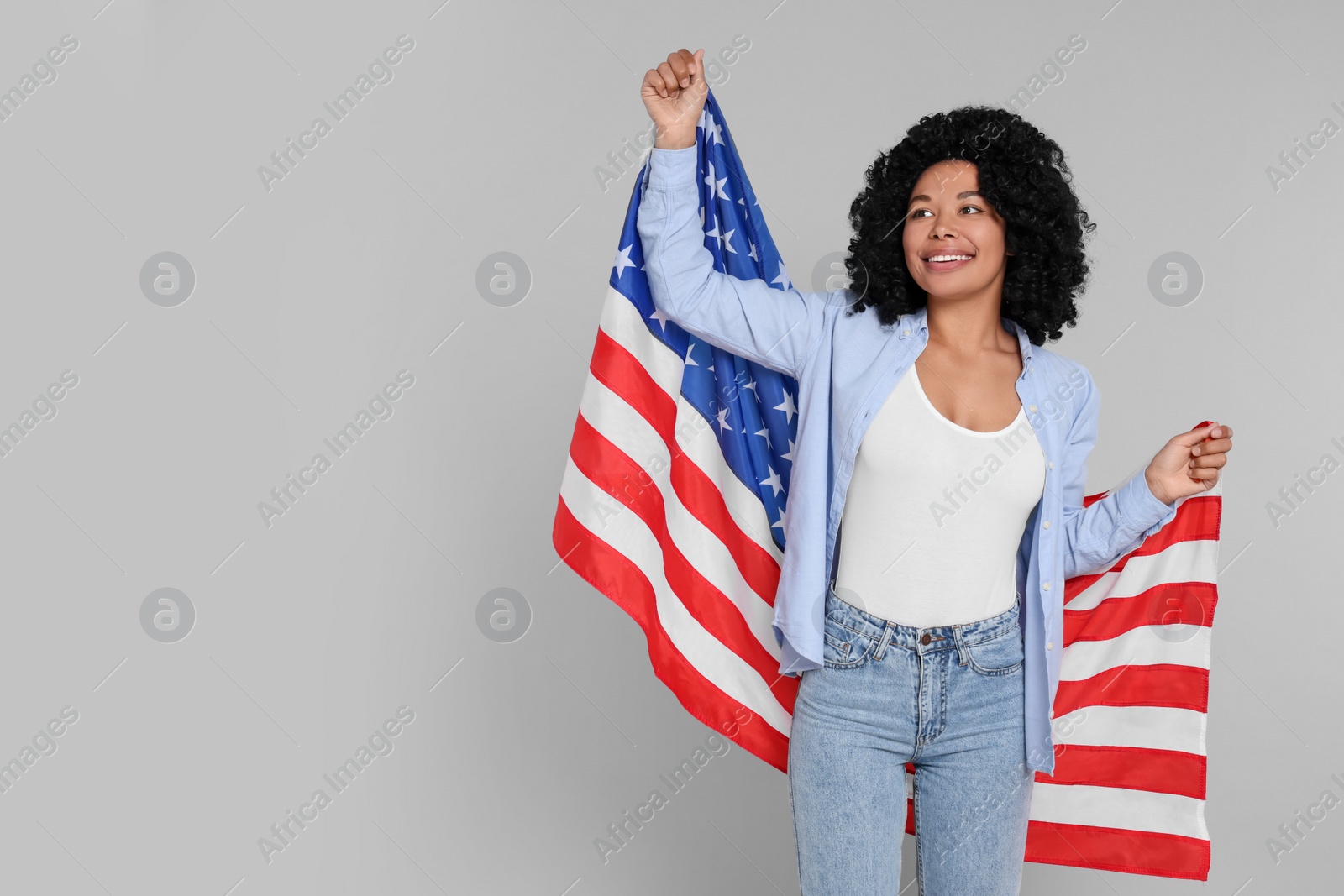 Photo of 4th of July - Independence Day of USA. Happy woman with American flag on light grey background, space for text