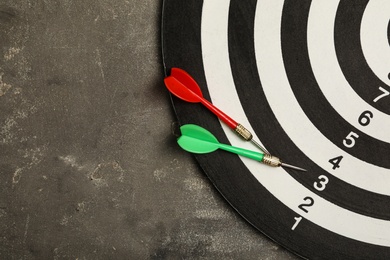 Photo of Dart board with color arrows on dark stone background, top view. Space for text